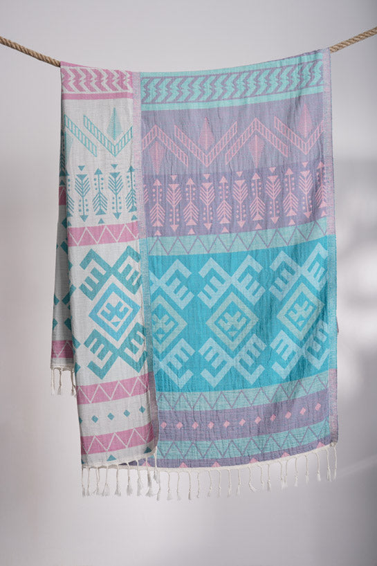 Colorful patterned towel with geometric designs hanging on a line against a neutral background