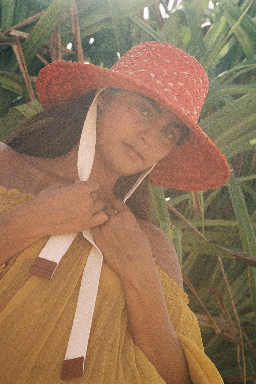 Woman wearing a red sun hat and yellow dress in a natural setting
