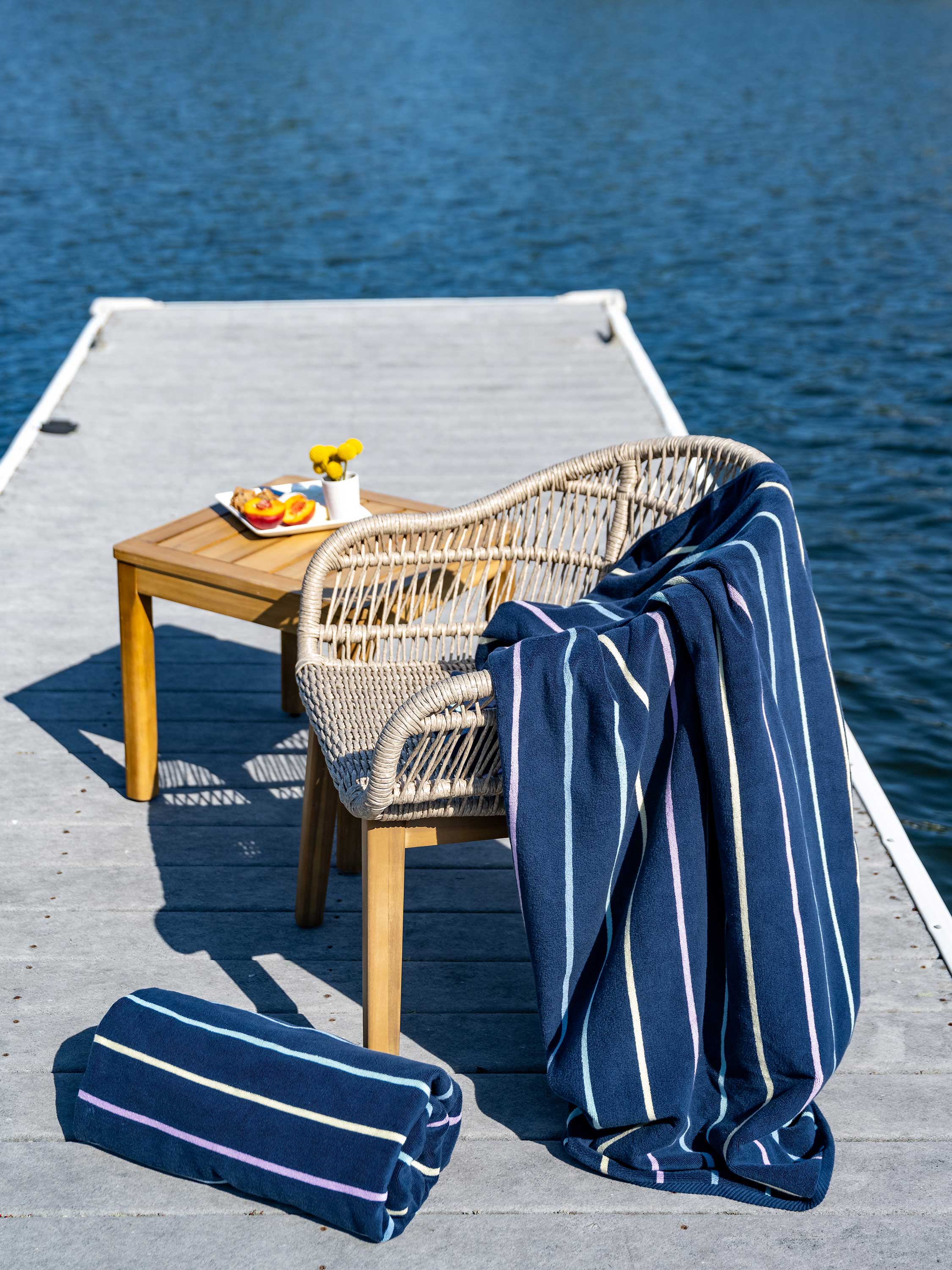 Navy striped towel draped over a chair on a dock with a table and snacks.
