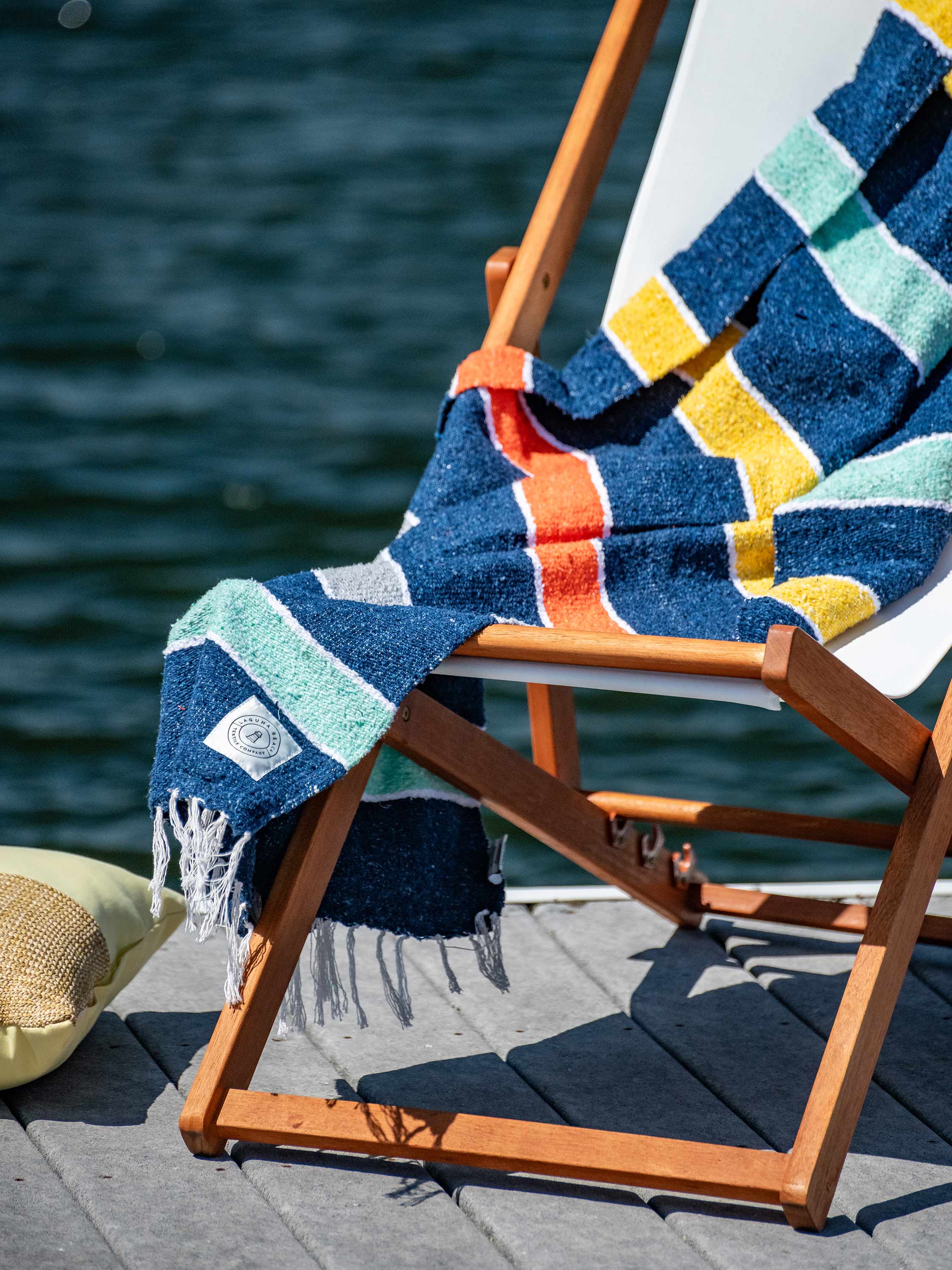 Colorful towel draped over a wooden chair by the water
