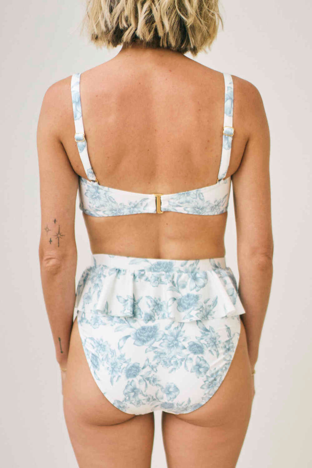 Person wearing a floral two-piece swimsuit against a plain background