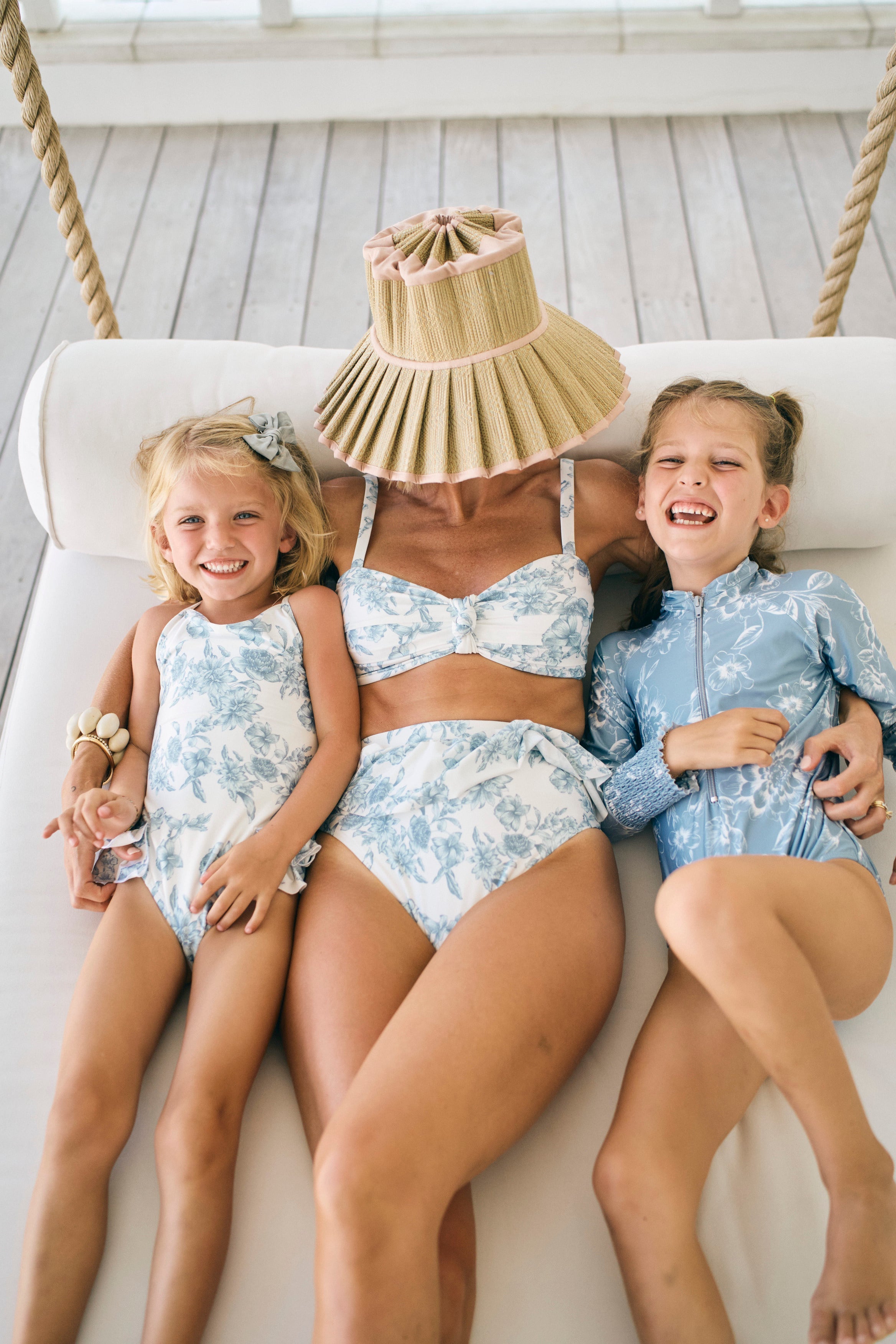 Three people in matching blue floral outfits sitting on a white couch.