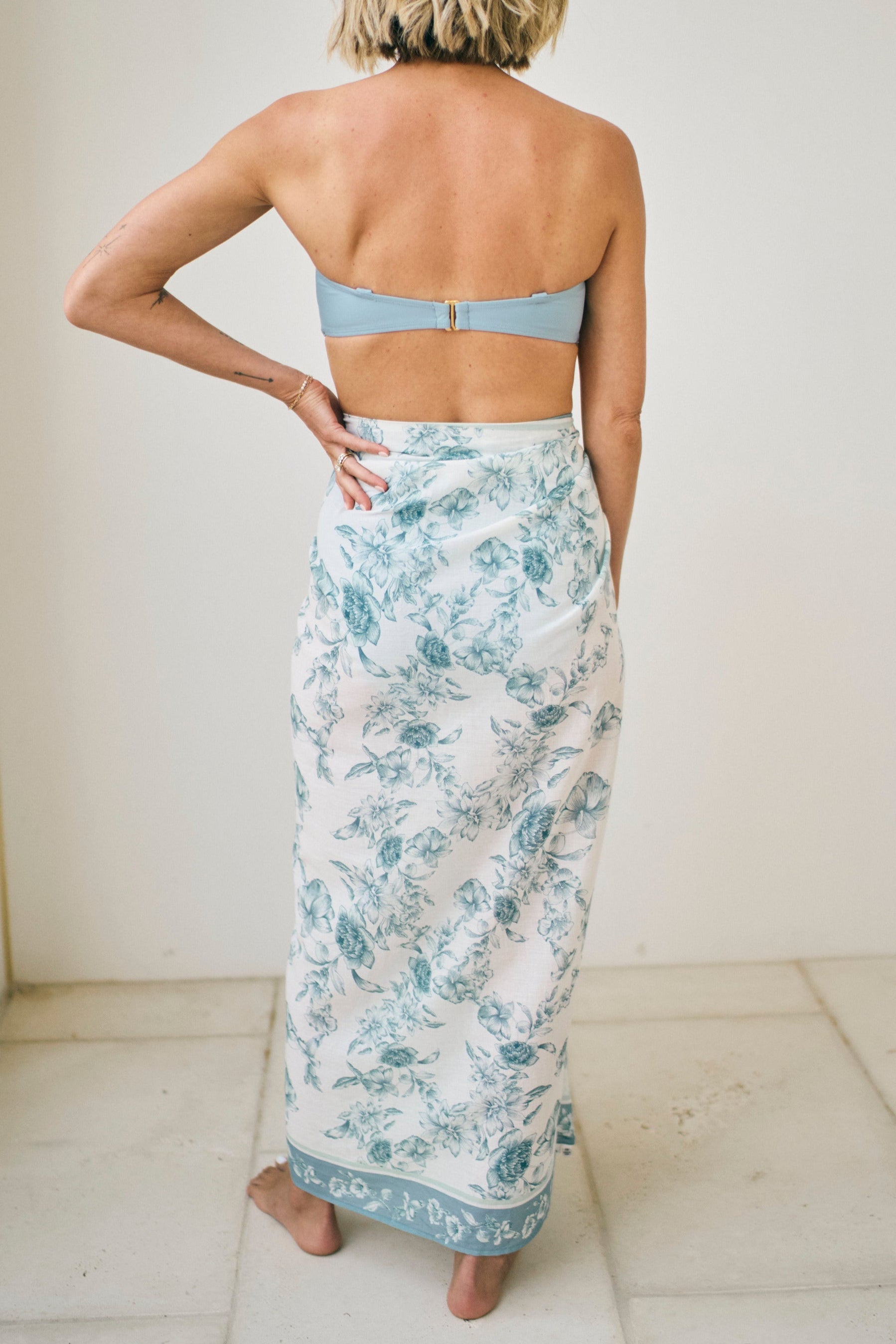 Woman wearing a floral skirt and light blue top against a white background