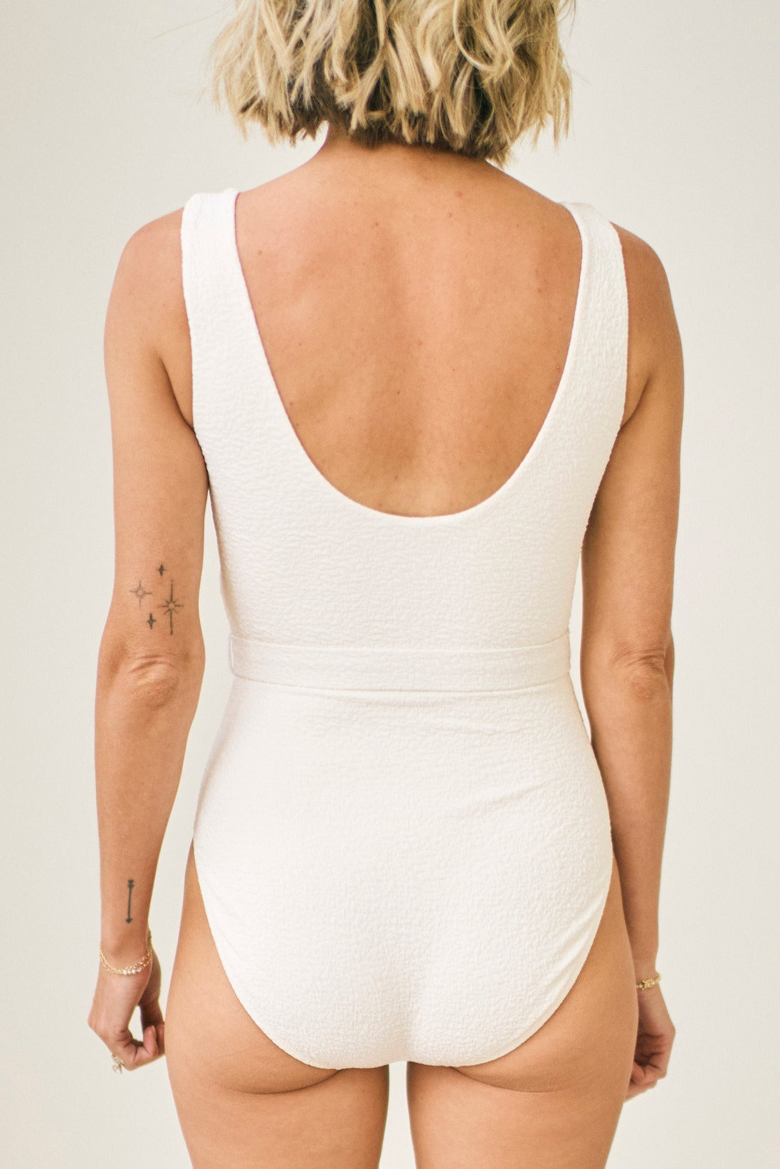 Person wearing a white swimsuit with a plain background