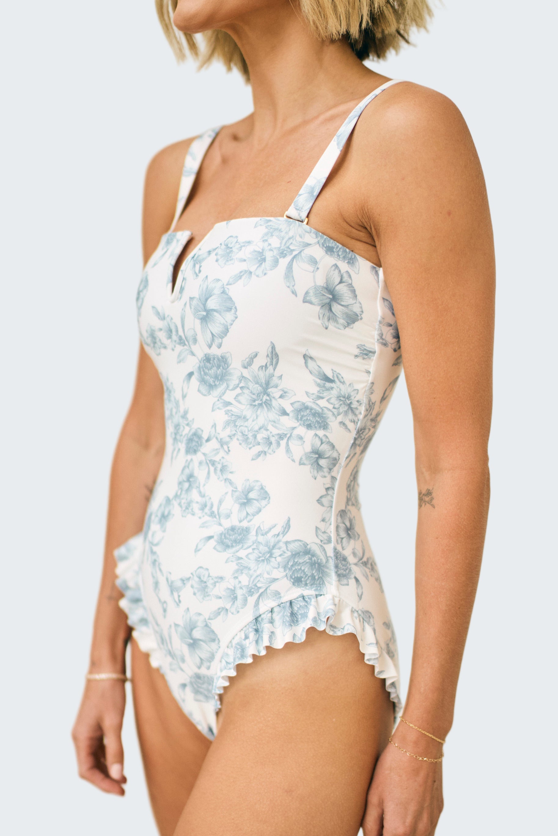 Woman wearing a blue floral swimsuit against a neutral background