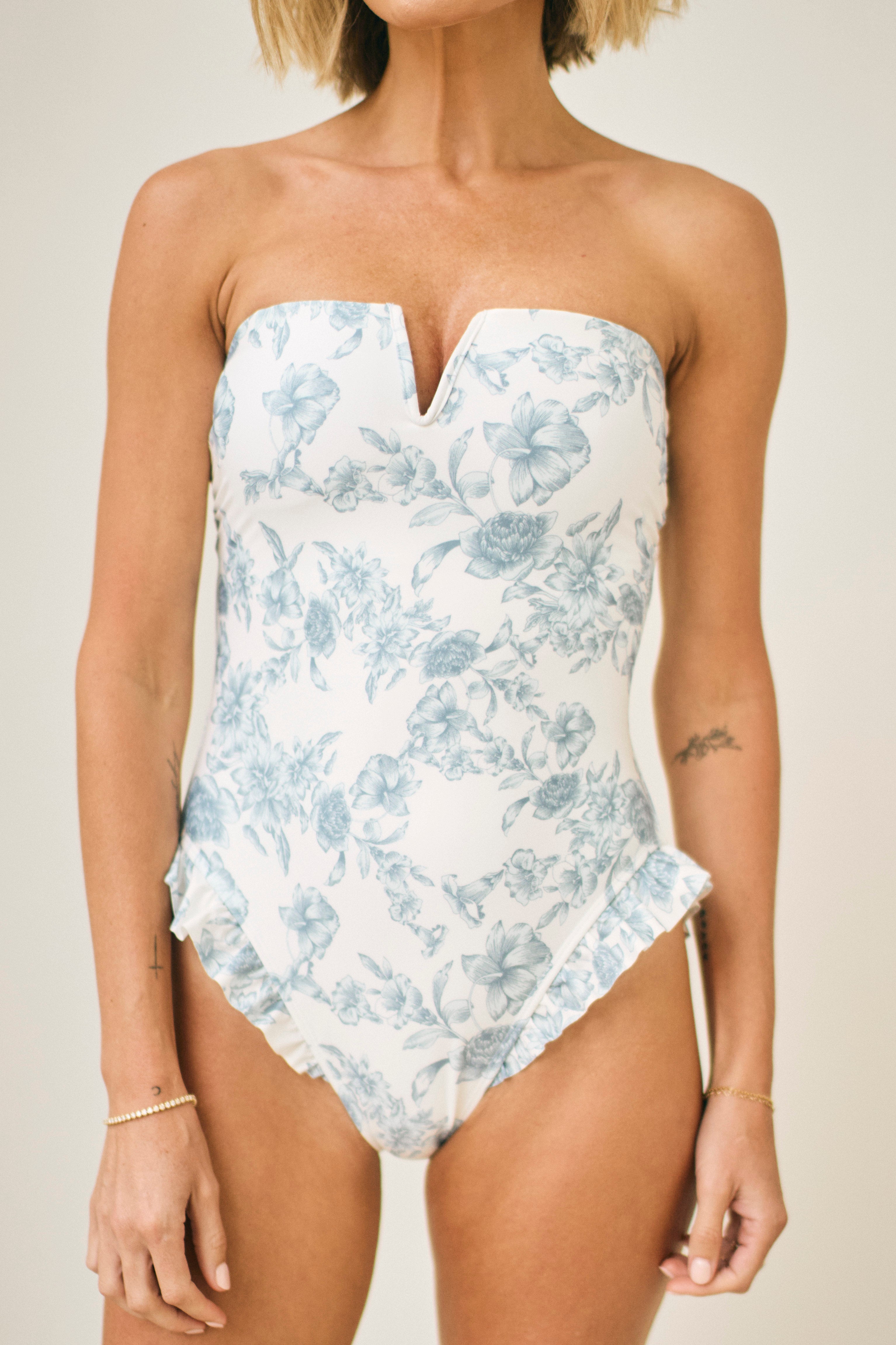 Woman wearing a strapless floral swimsuit against a neutral background