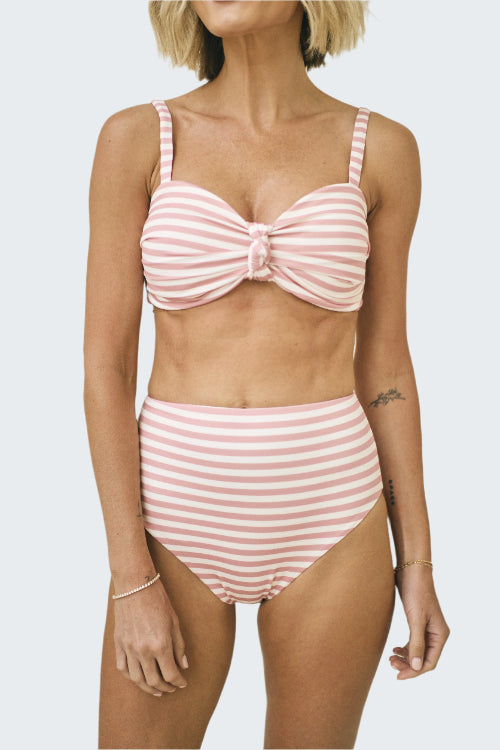 Woman wearing a pink and white striped bikini set against a neutral background