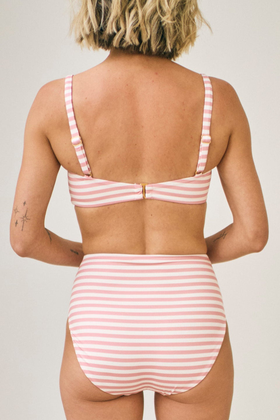 Person wearing a pink and white striped bikini set on a plain background