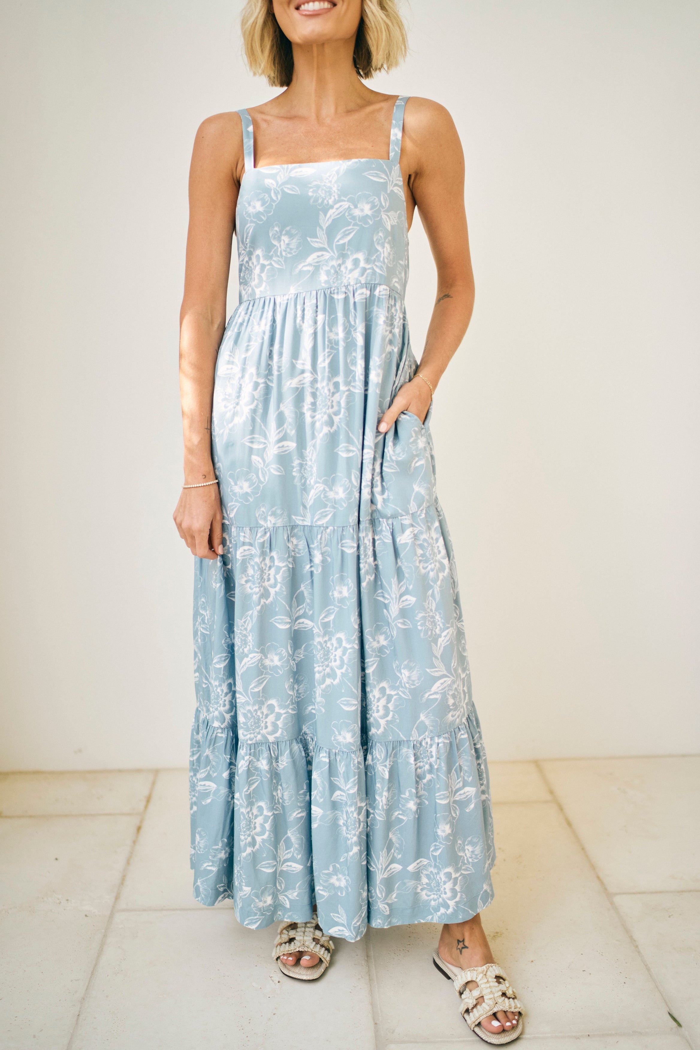 Woman wearing a light blue floral dress against a white background