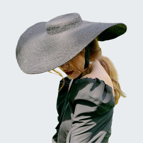 Person wearing a large gray sun hat in a garden setting