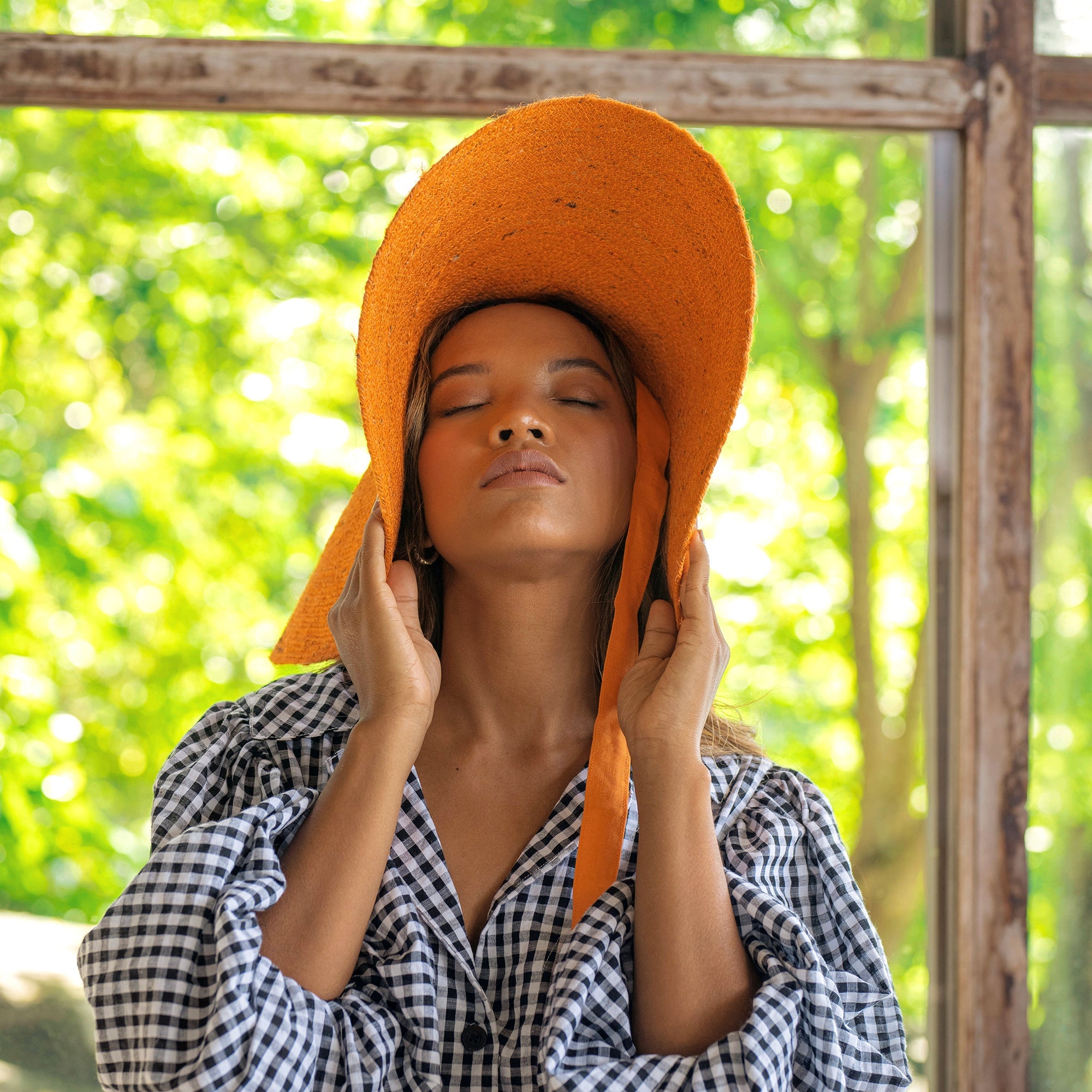 Woman wearing an orange hat with a blurred green outdoor background