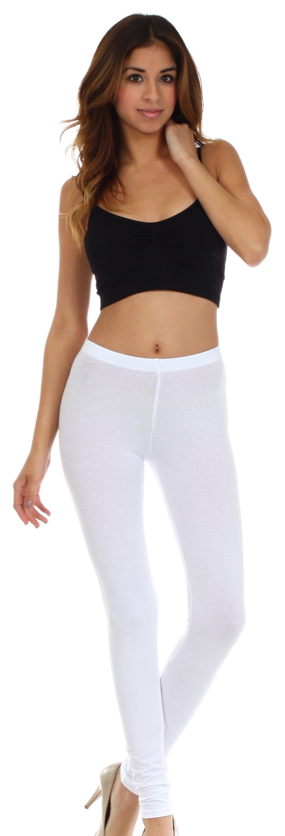 Woman wearing a black sports bra and white leggings on a white background