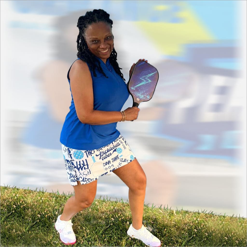 Woman holding a pickleball paddle on a grassy area with a blurred background