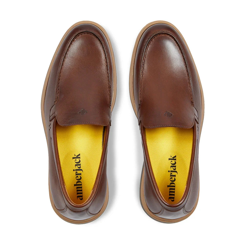 Brown leather loafers with yellow soles on a white background