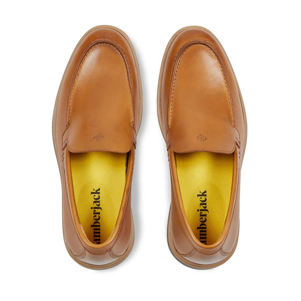 Pair of brown leather loafers with yellow interior on a white background