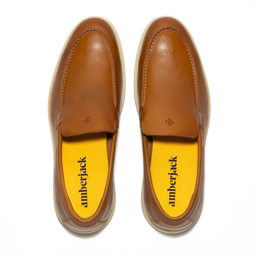 Pair of brown leather loafers with yellow insole on a white background