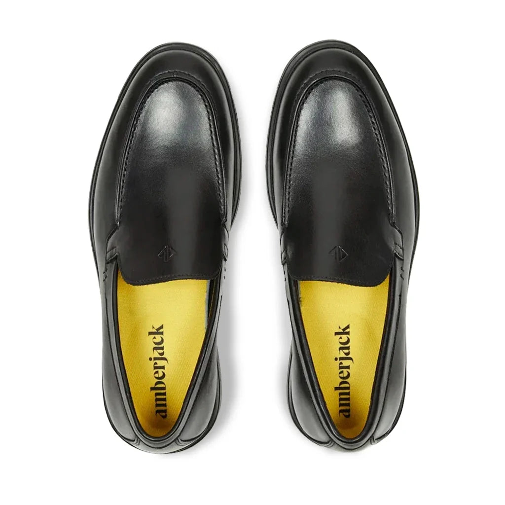 Black leather shoes with yellow soles on a white background