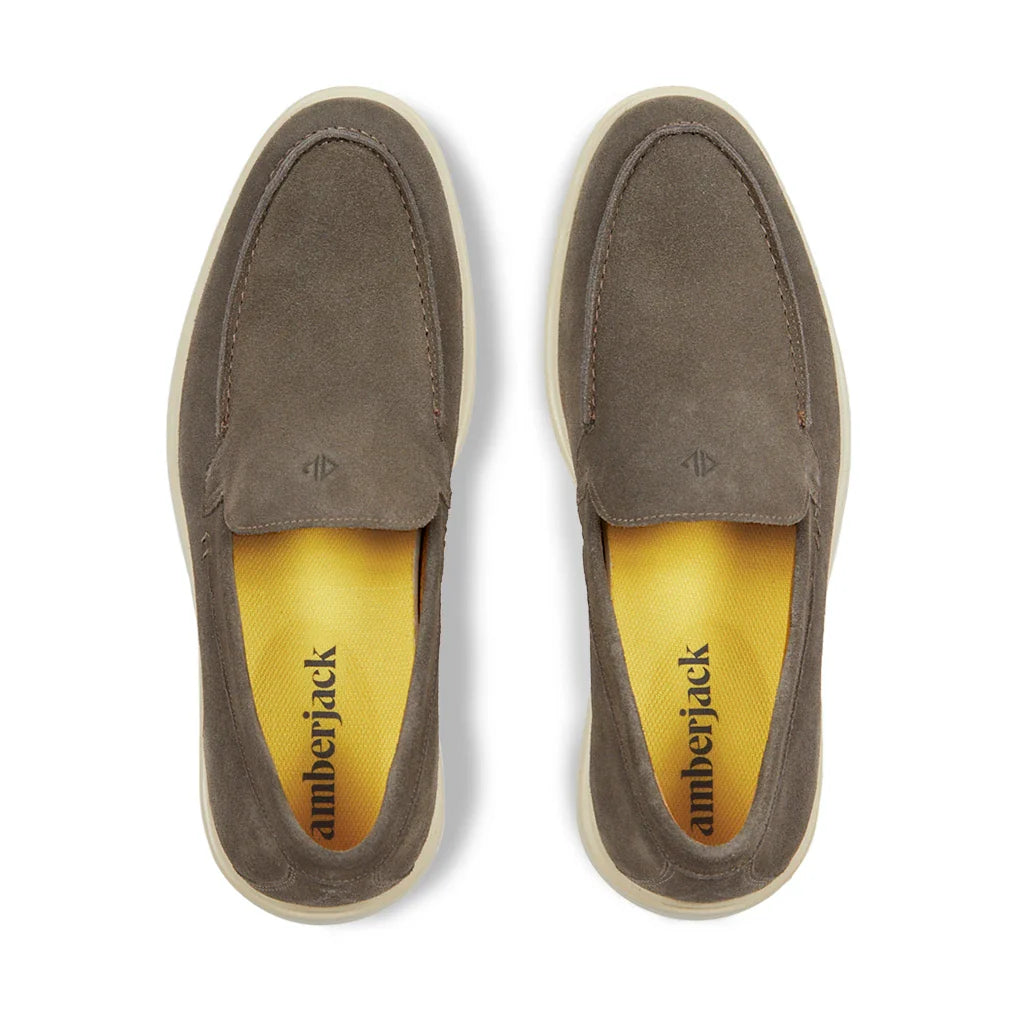 Pair of brown suede loafers with yellow interior on a white background