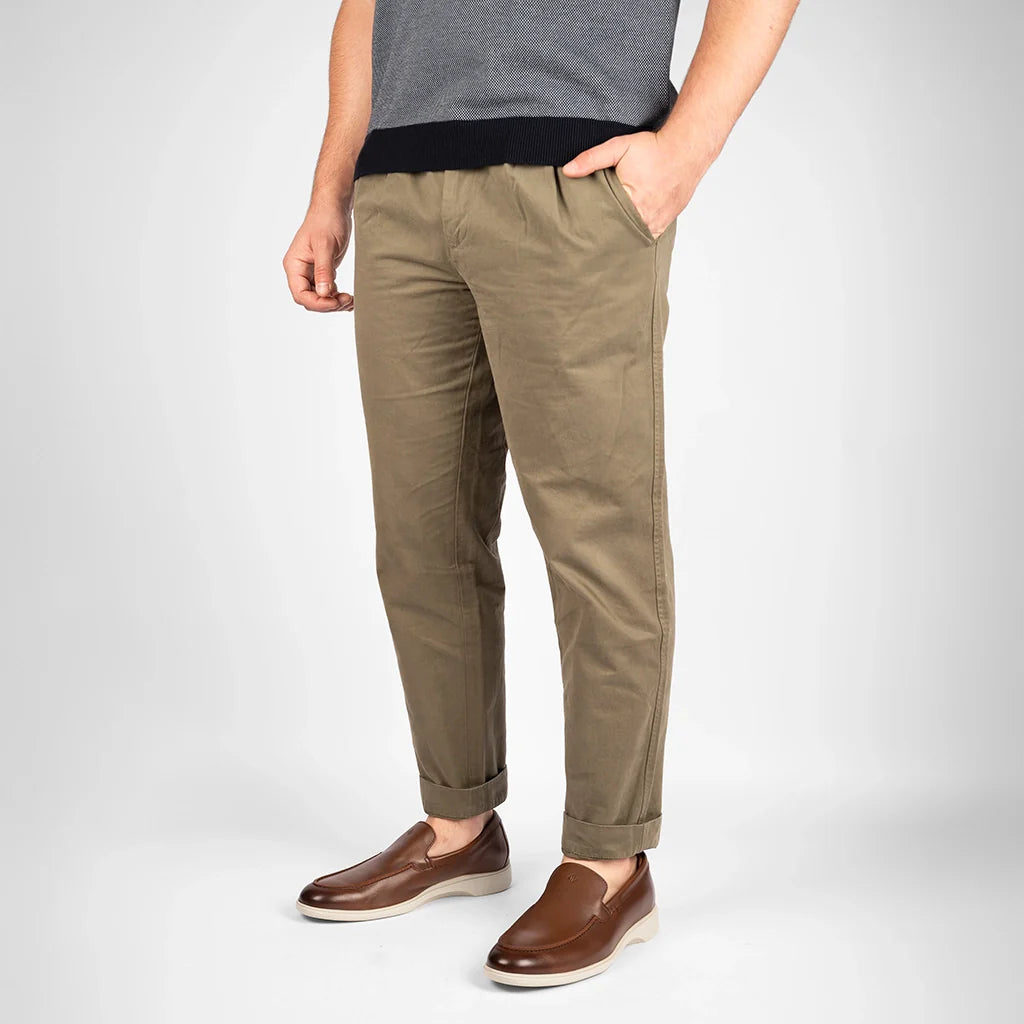 Person wearing khaki pants and brown shoes on a white background
