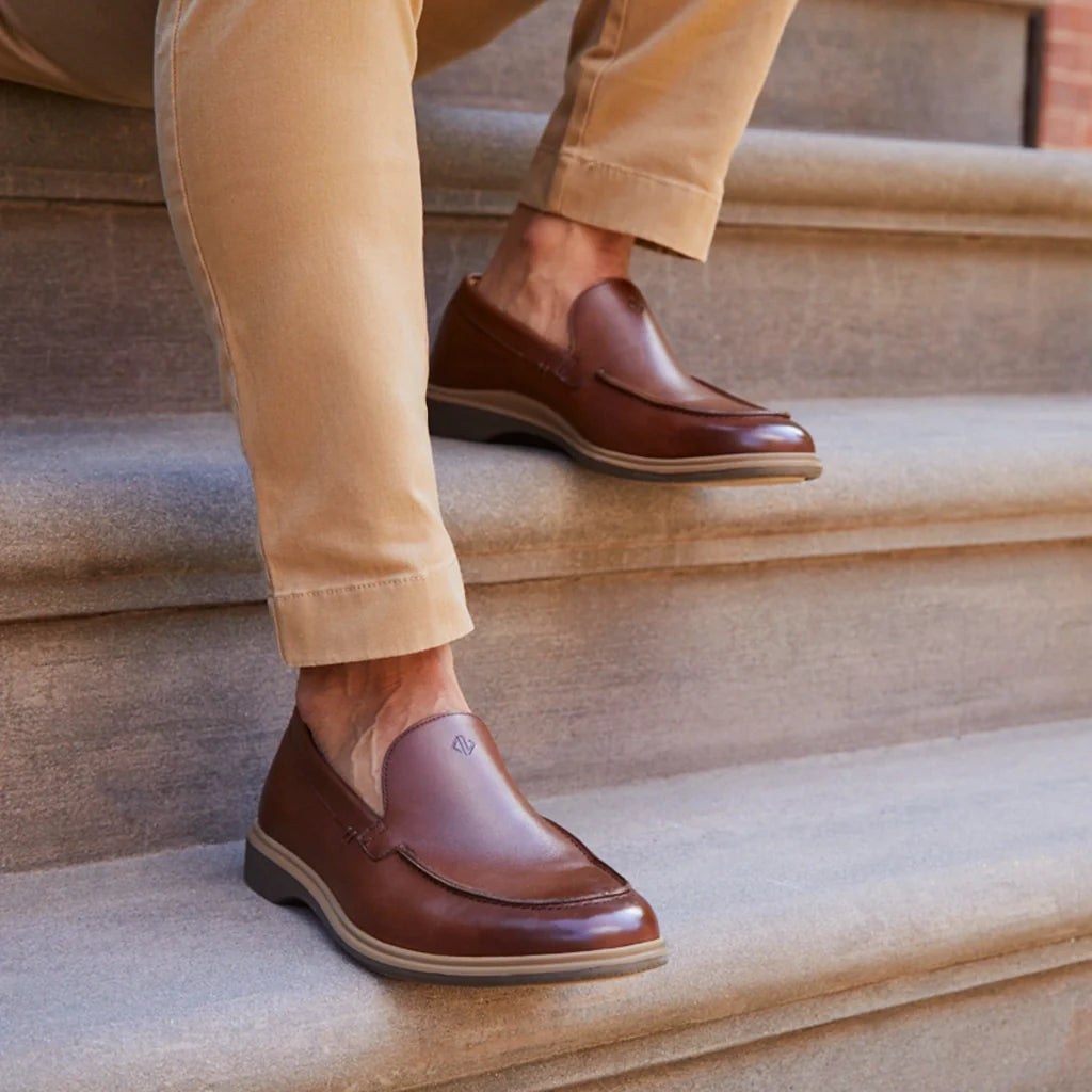Brown leather shoes worn with beige pants on stone steps