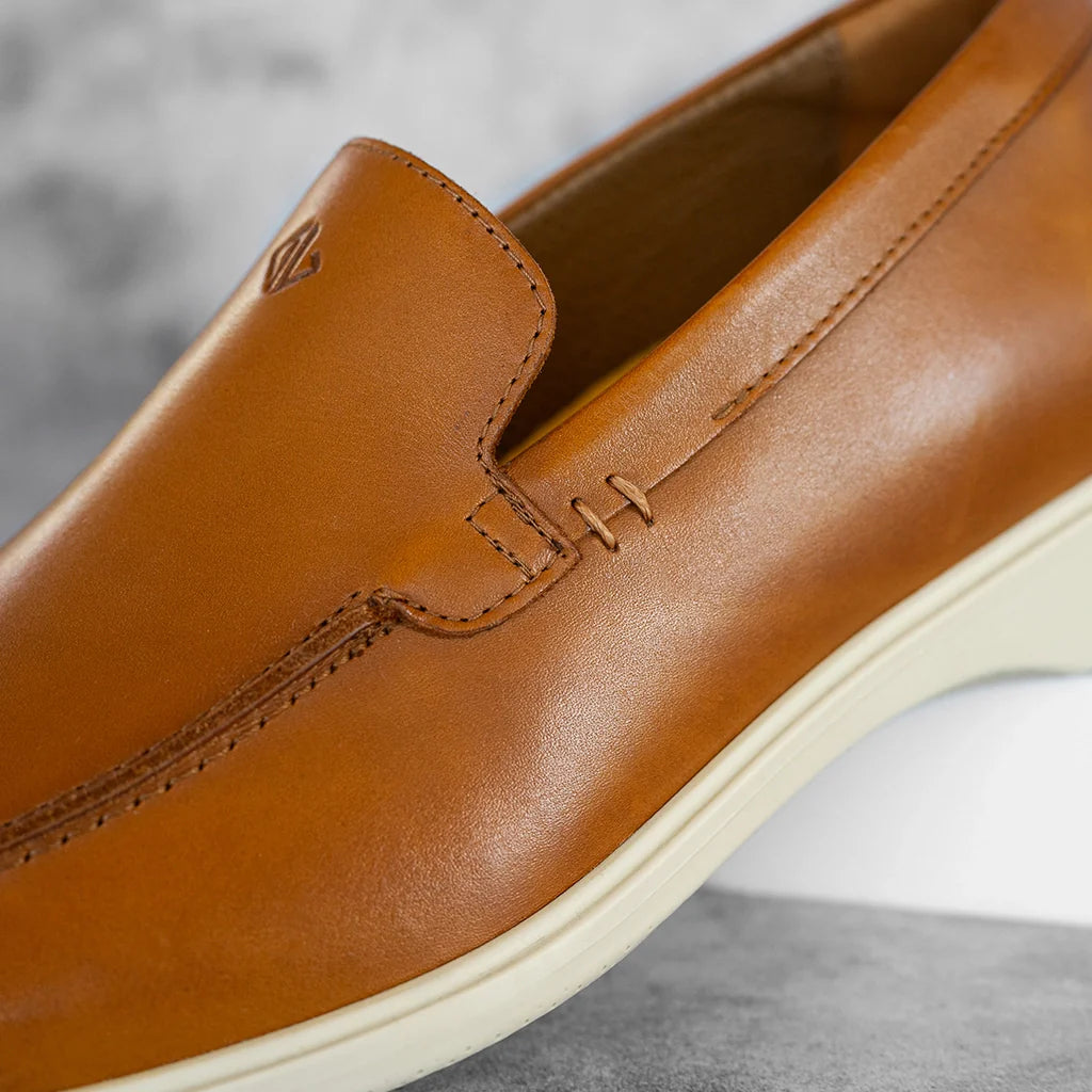 Close-up of a brown leather loafer shoe on a gray background