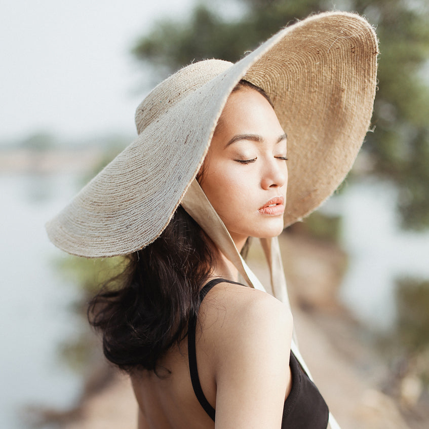 Woman wearing a large straw hat with a blurred natural background