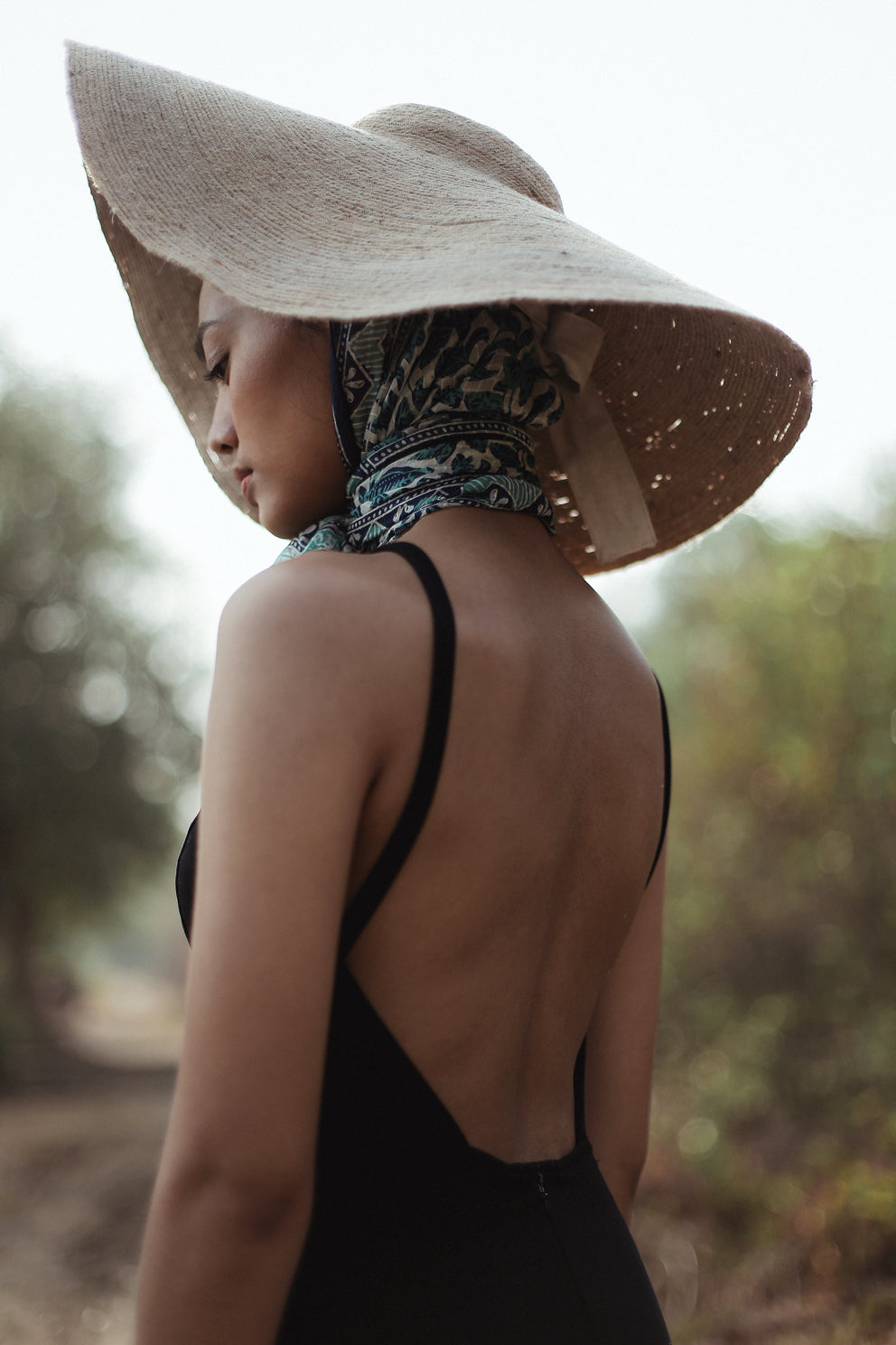 Woman wearing a wide-brimmed hat and black dress in a natural setting