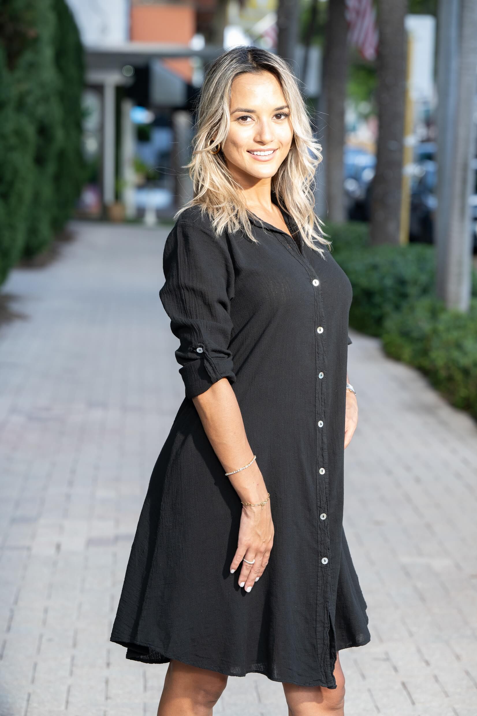 Woman wearing a black dress on a sidewalk with blurred background