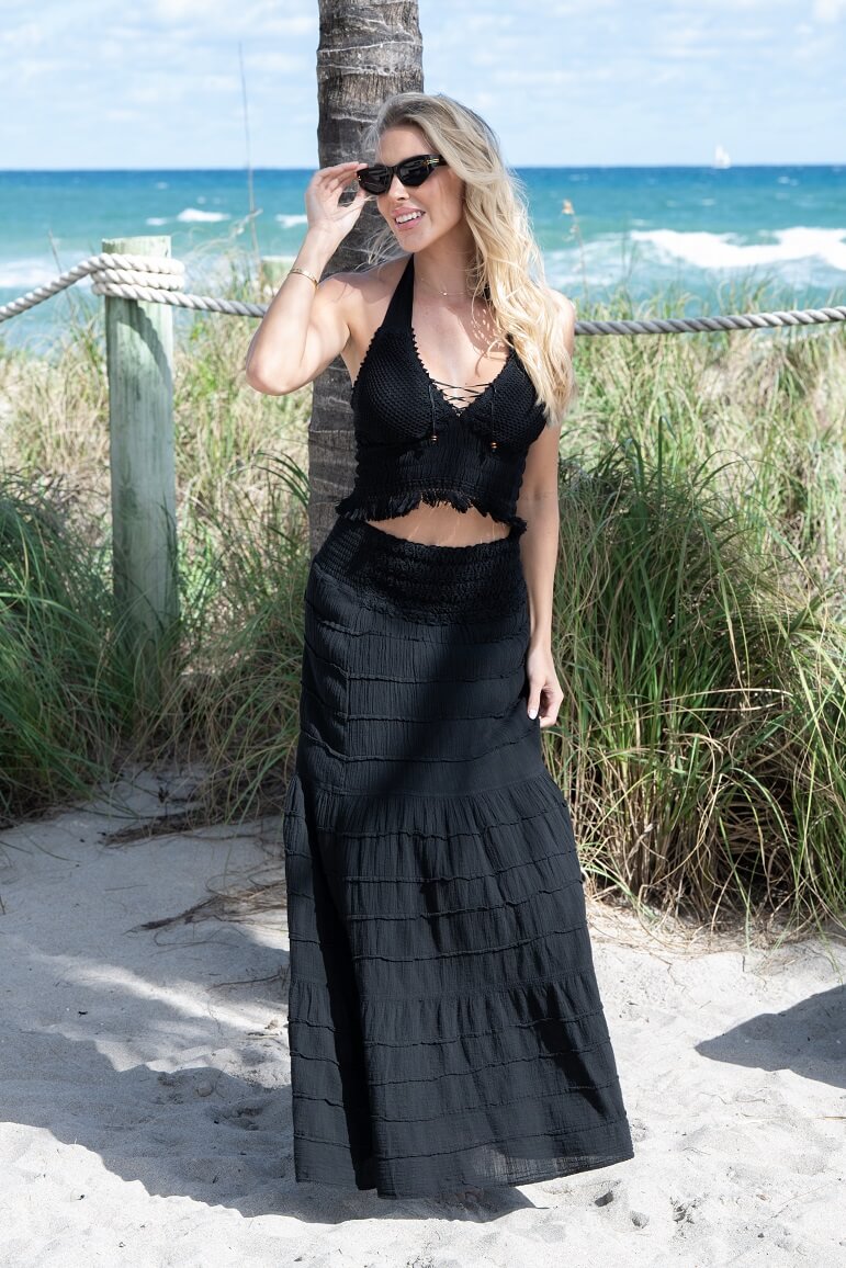 Woman in a black outfit standing on a beach with ocean in the background