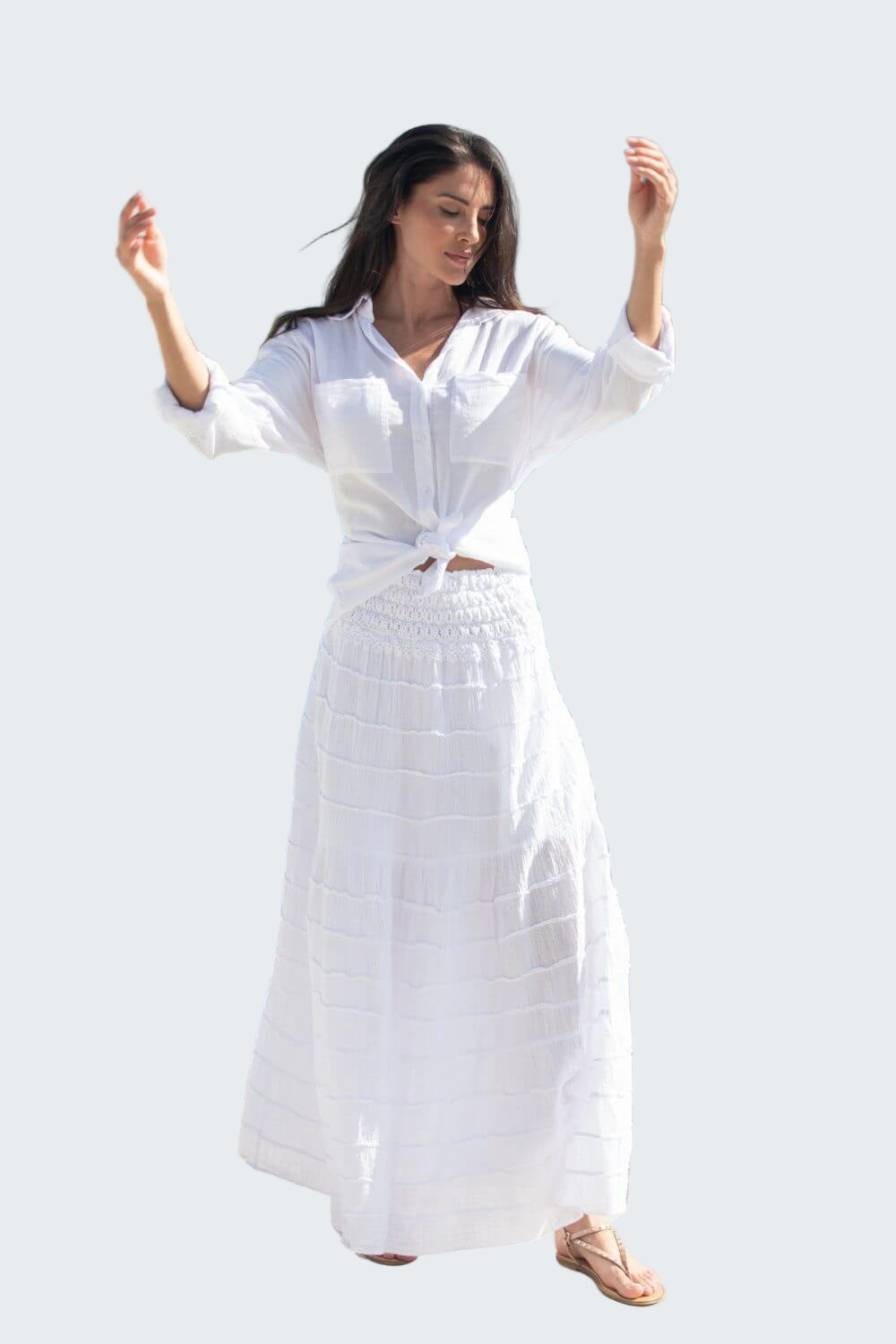 Woman in a white dress standing by a waterfront with buildings in the background