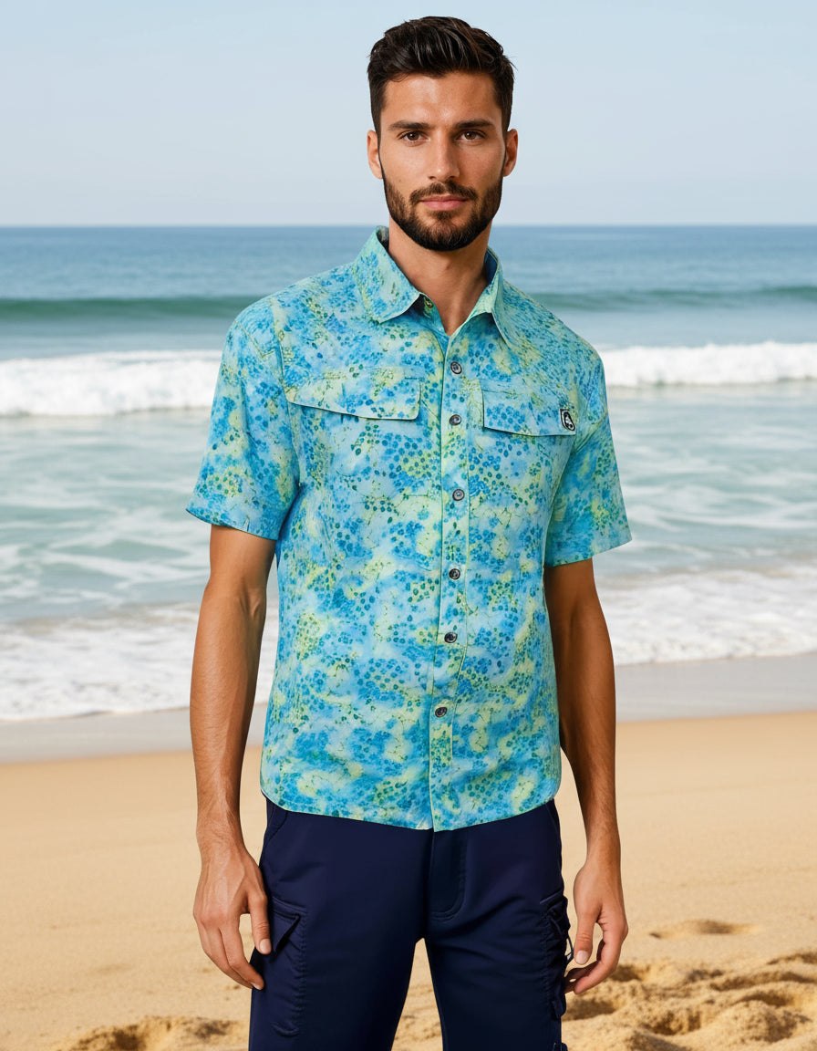 Man wearing a blue patterned shirt and navy pants on a white background