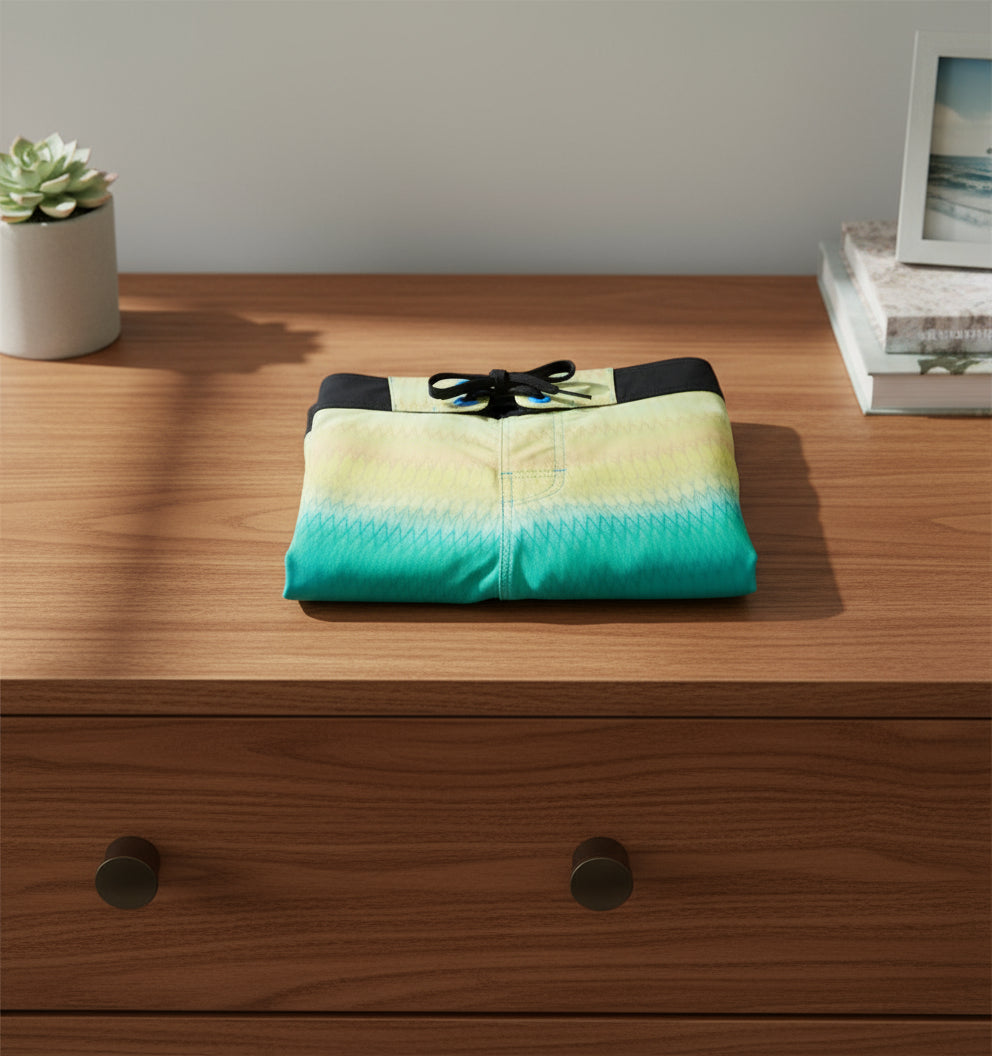 Gradient blue and yellow board shorts with black accents on a white background