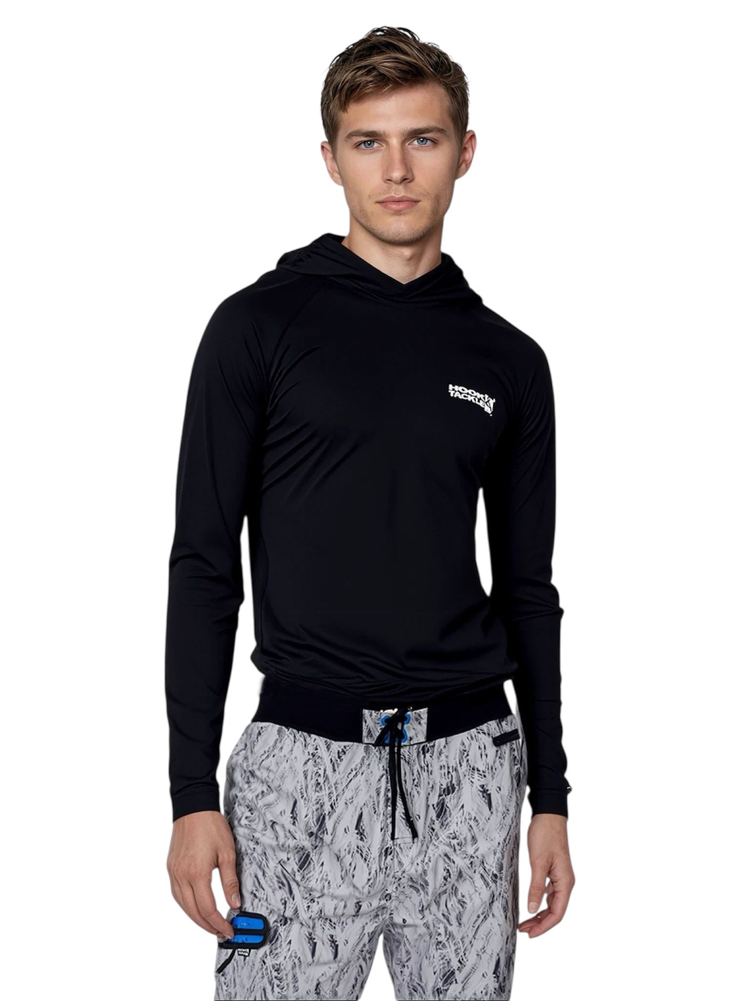 Man wearing a black hoodie with a logo and patterned pants on a white background