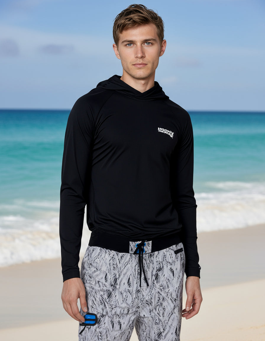 Man wearing a black hoodie with a logo and patterned pants on a white background