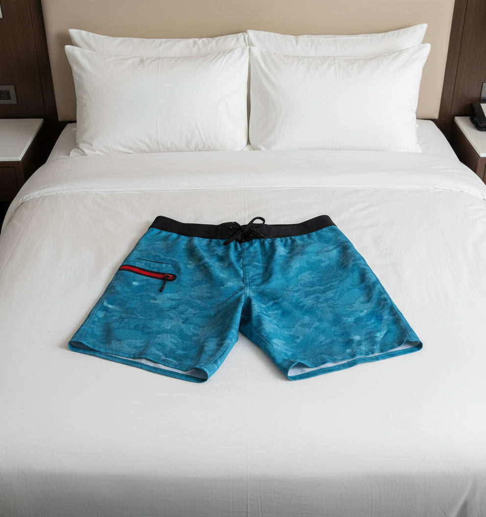 Blue camouflage shorts with a black waistband and red zipper on a white background