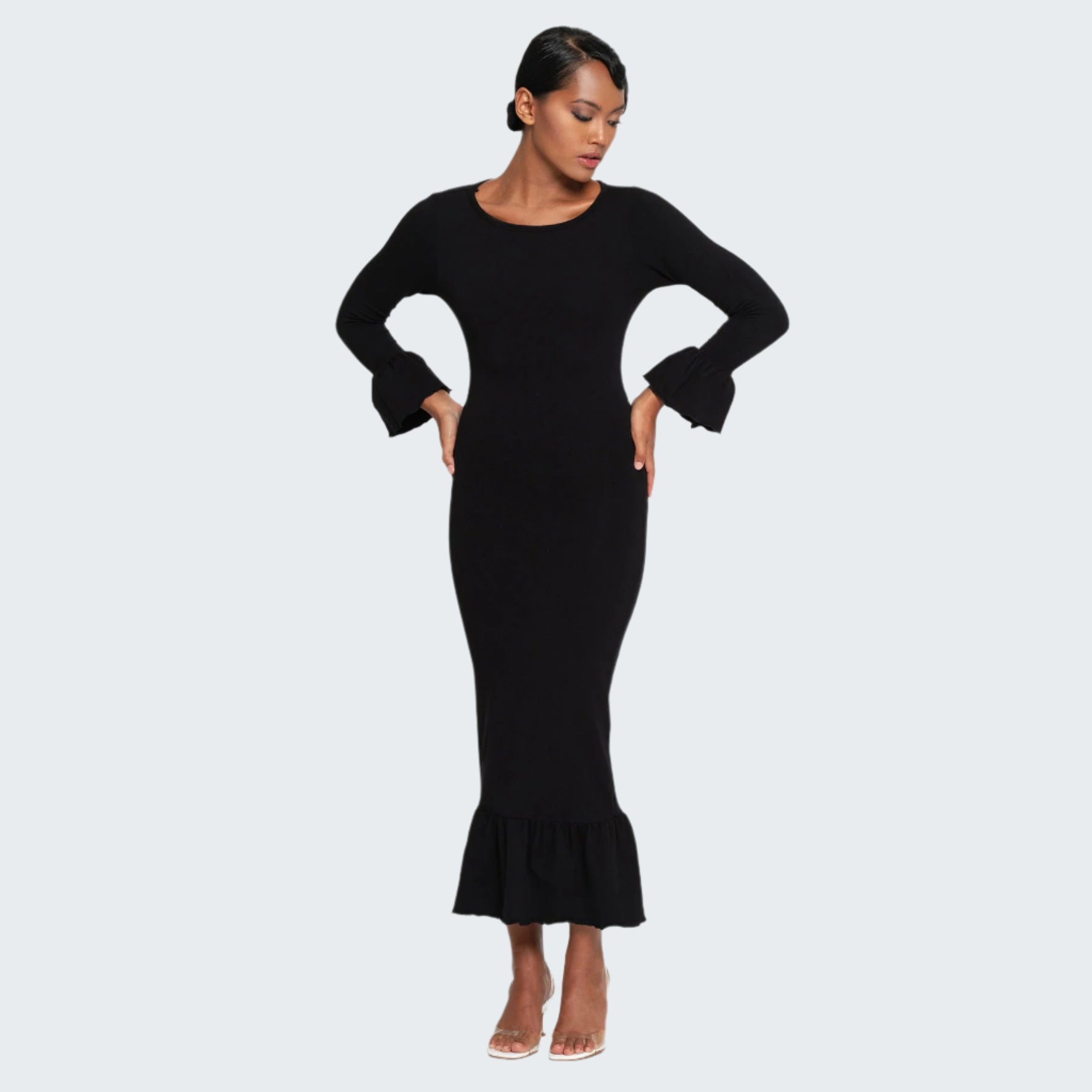 Woman wearing a black dress with ruffled hem on a white background