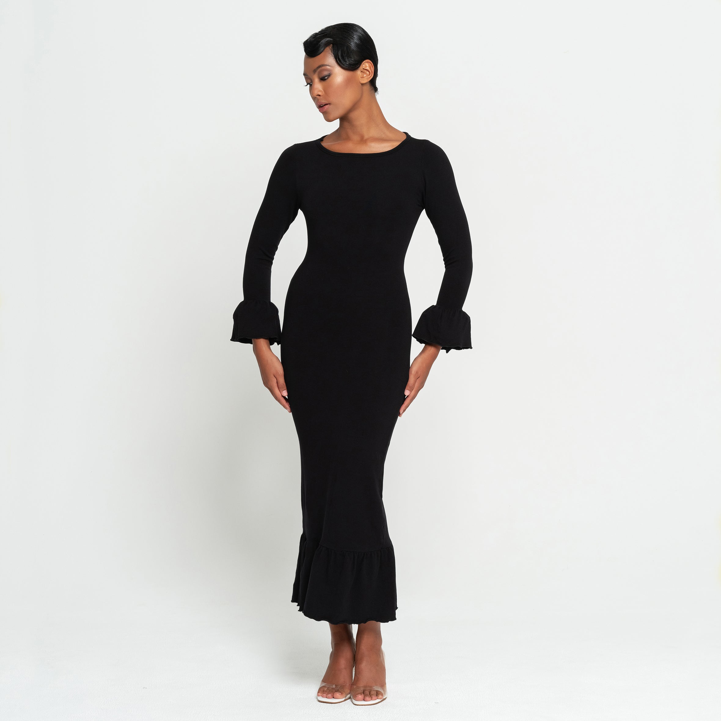 Woman wearing a black dress with long sleeves on a white background