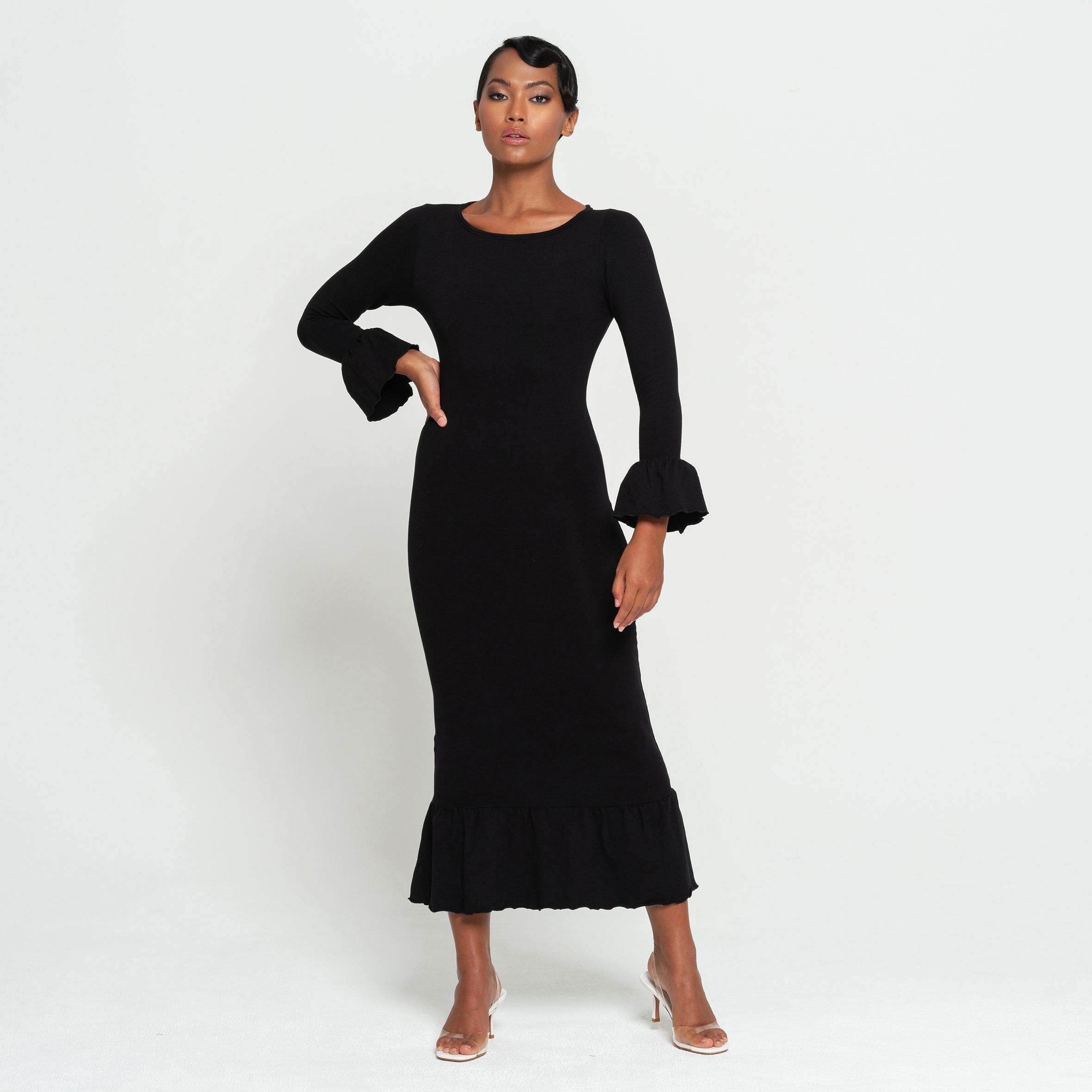 Woman wearing a black dress with ruffled sleeves on a white background
