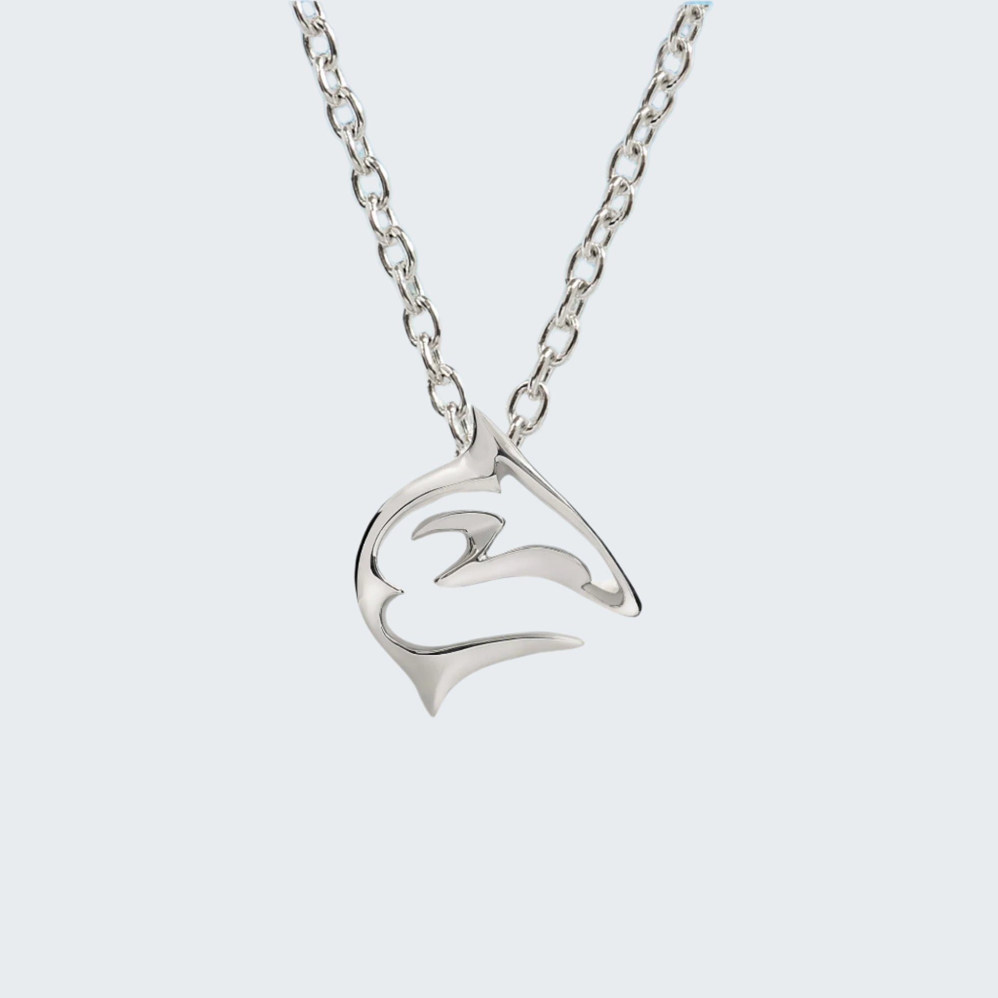 Silver necklace with a dolphin pendant on a sandy beach with ocean in the background