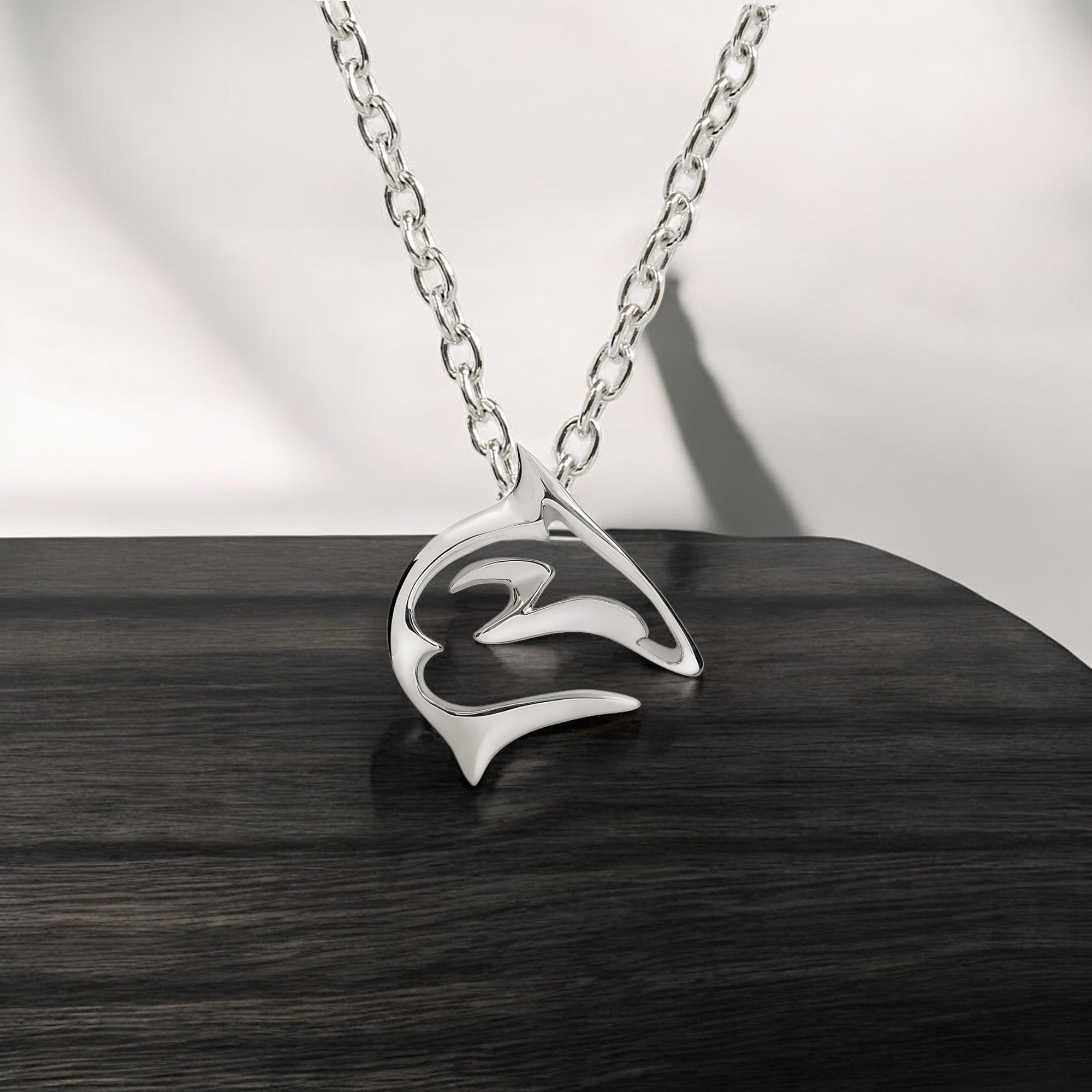 Silver necklace with a heart-shaped pendant on a wooden surface