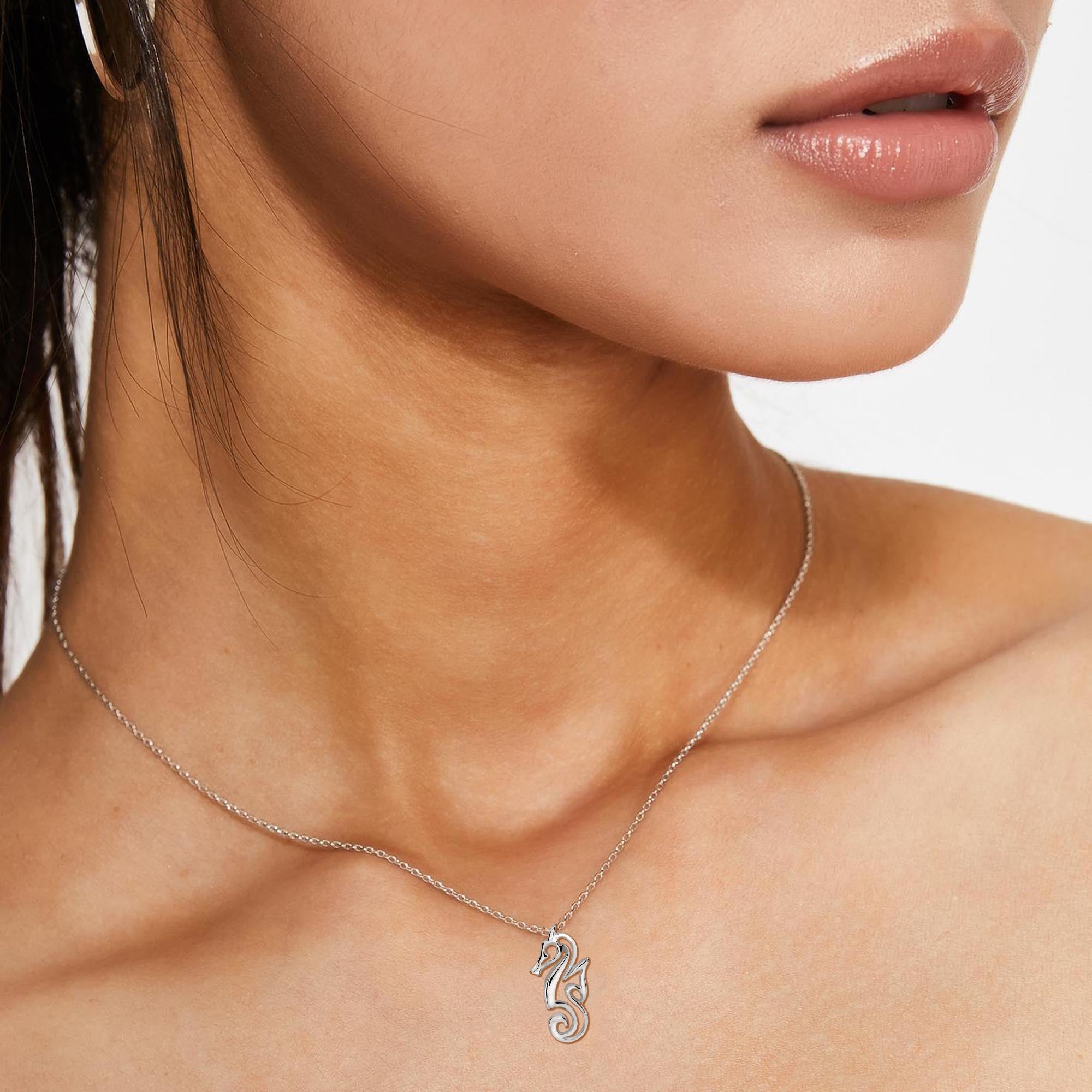 Silver necklace with a seahorse pendant worn by a person