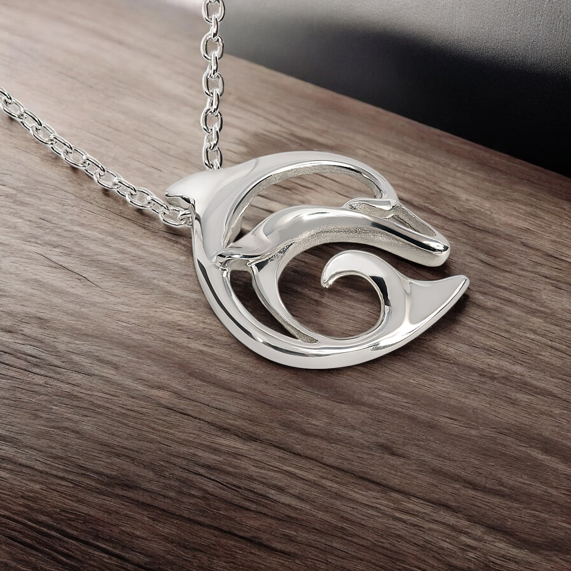 Silver dolphin pendant necklace on a wooden surface