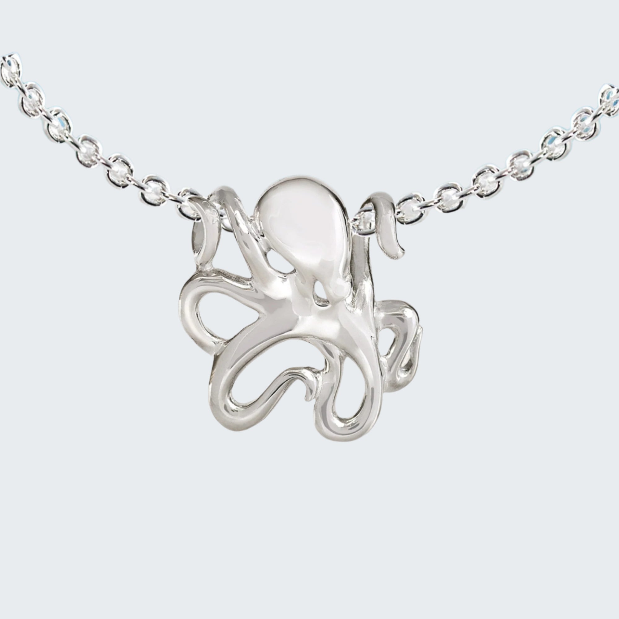 Silver octopus necklace on a chain with a beach background