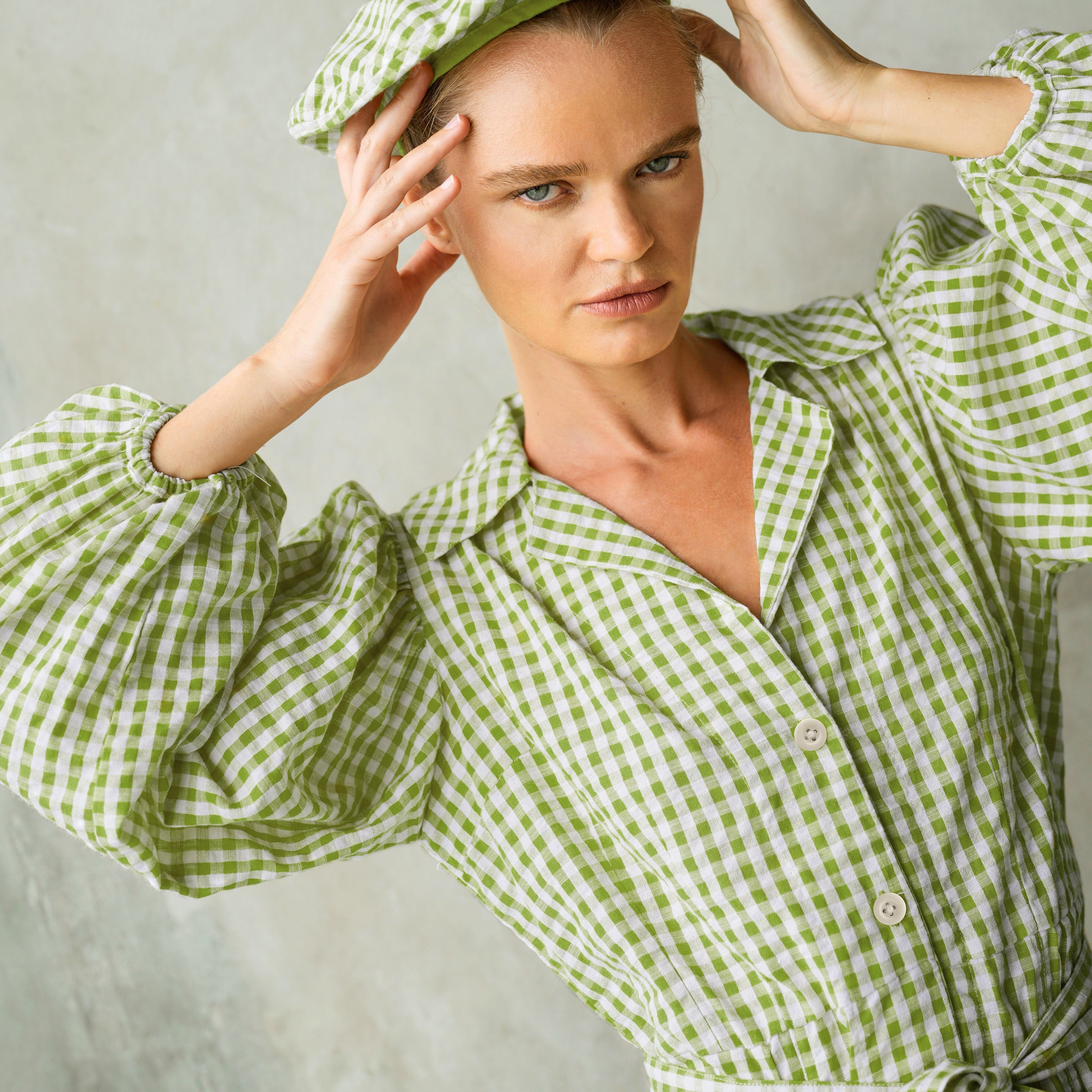 Woman wearing a green and white checkered outfit against a neutral background
