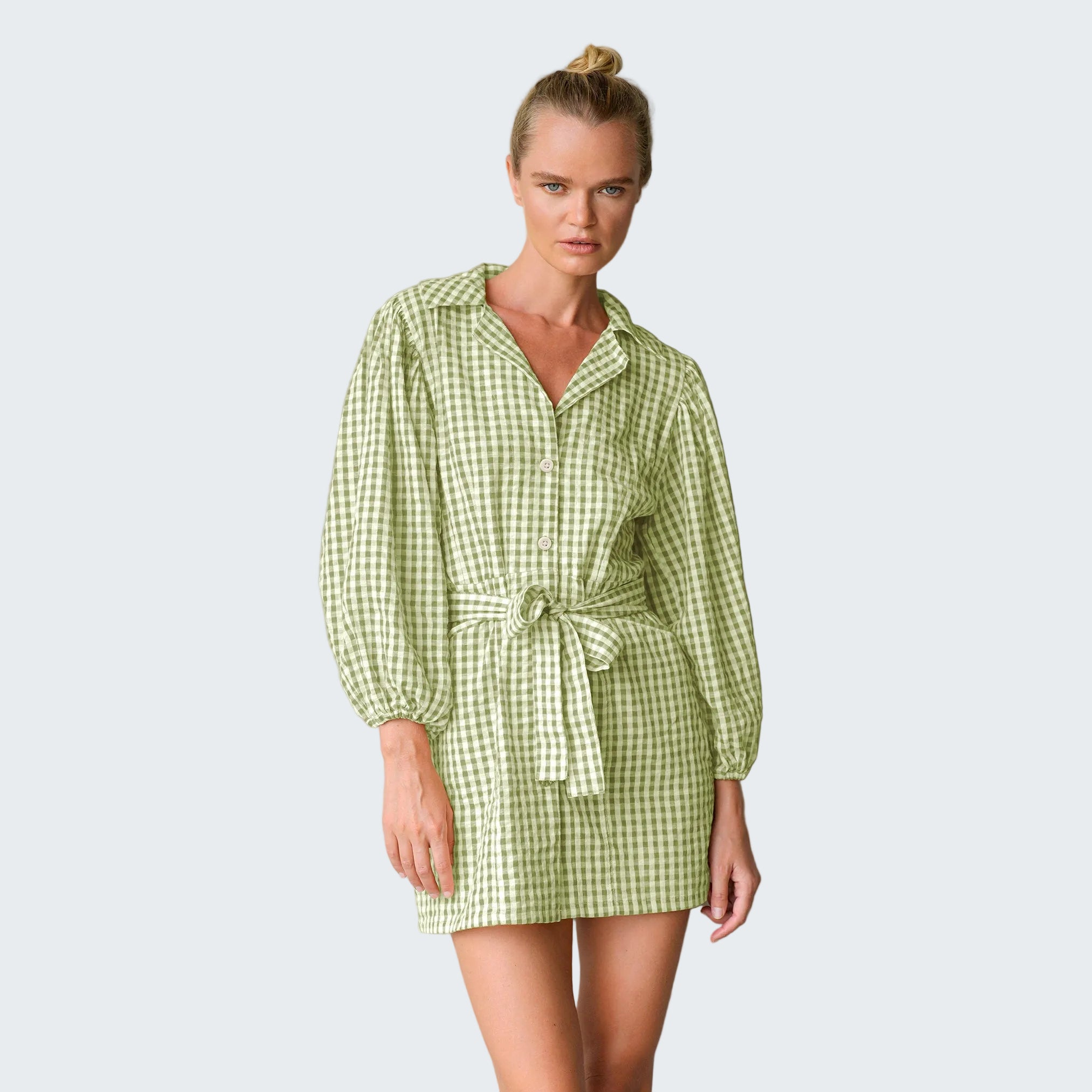 Woman wearing a green checkered dress against a gray background