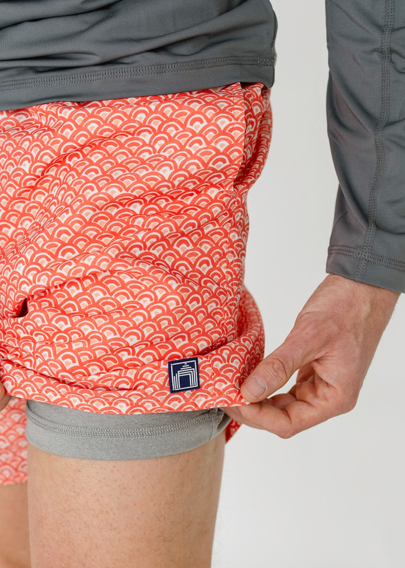 Person wearing red patterned shorts with a visible brand logo on a white background