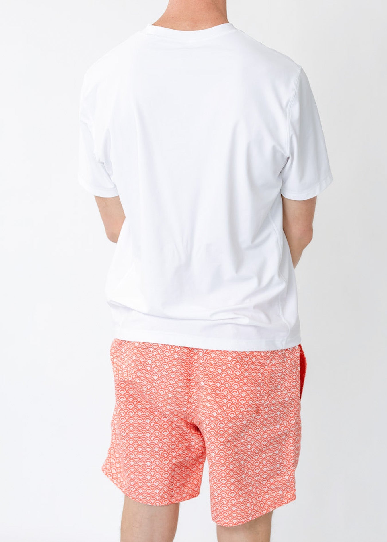 Person wearing a white t-shirt and red patterned shorts on a white background