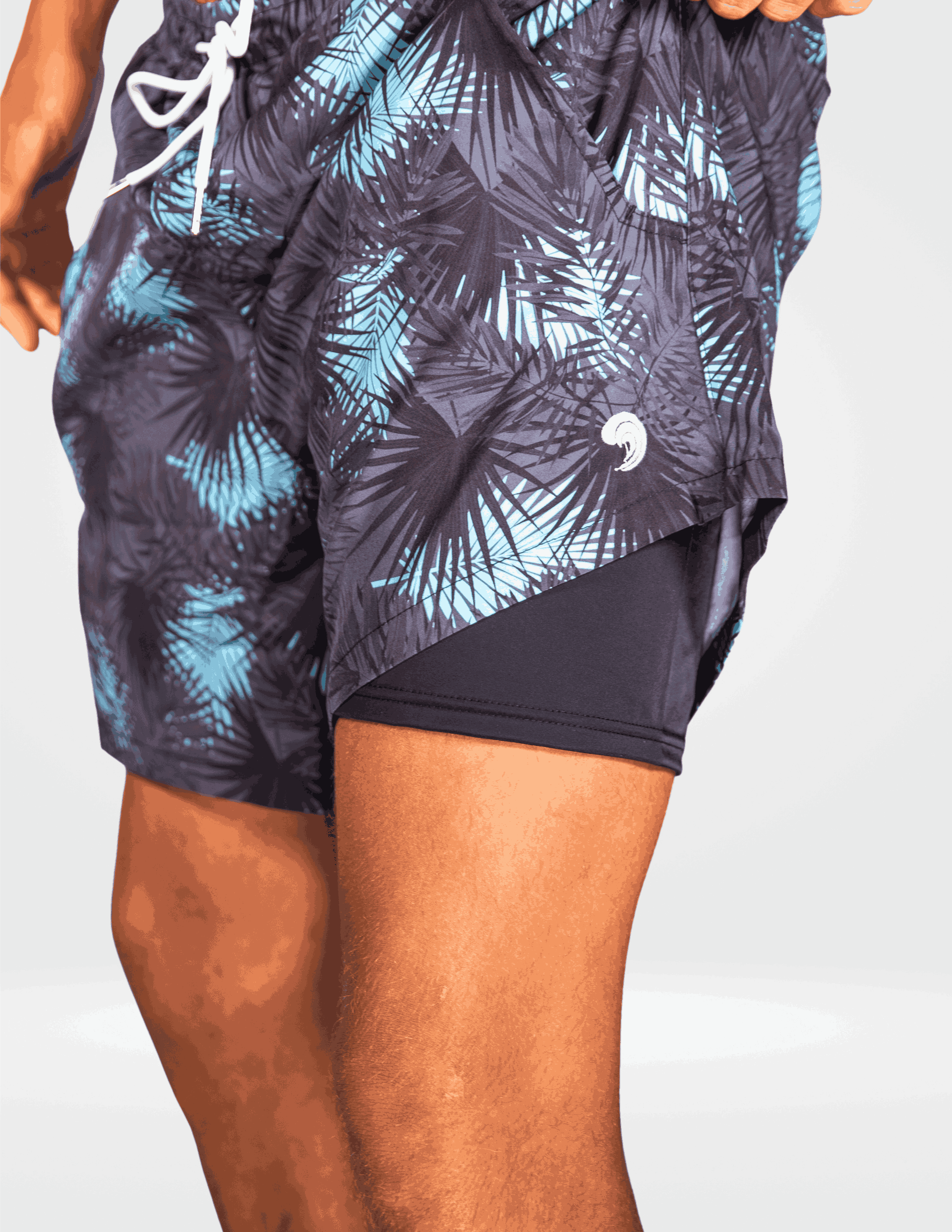 Person wearing a pair of black and blue leaf-patterned shorts on a white background