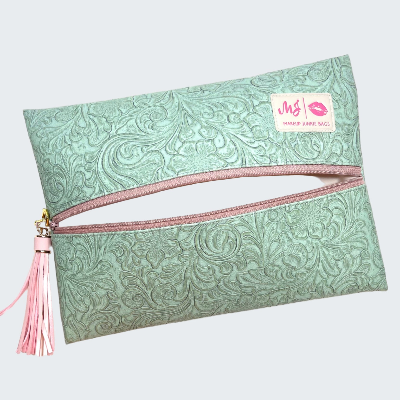 Green patterned pouch with pink zipper and tassel on a white background