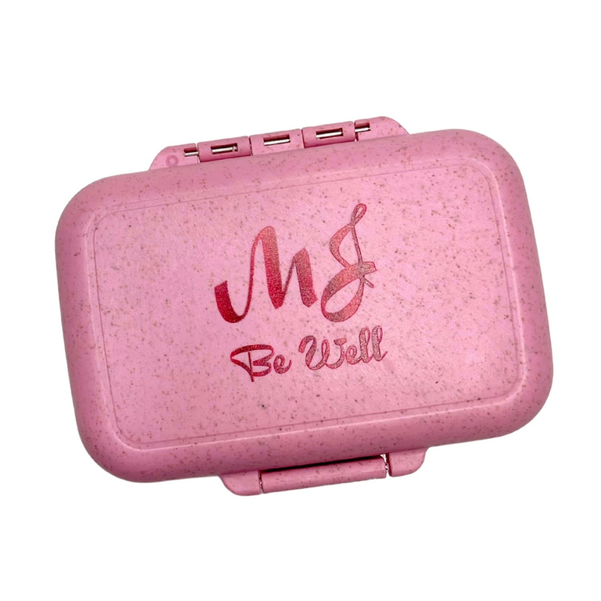 Pink pill box with 'MG Be Well' text on a white background